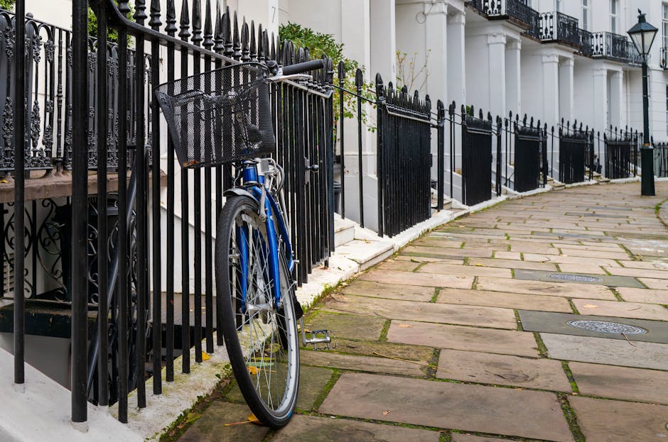 A rectangular metal sign affixed to a brick wall, featuring black and red lettering. The sign displays the text 'Welcome to South Kensington SW7,' with 'South Kensington' in large bold black font, 'Welcome to' in smaller red font above, and the postal code 'SW7' in red at the bottom right corner. The brick wall behind the sign is composed of uniformly textured reddish-brown bricks with visible mortar lines, providing a traditional and durable background. The sign and bricks are well-maintained, indicating regular cleaning and upkeep, typical in residential or commercial premises in West Kensington. West Kensington Cleaners emphasizes surface cleaning and sanitisation, ensuring surfaces like brick, metal, and signage remain clean and presentable for tenants and visitors.